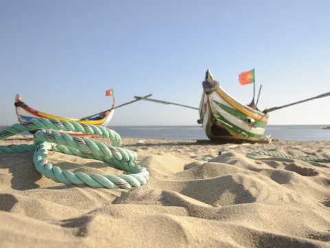 Barca con bandera de Portugal situada en la playa de Nazaré