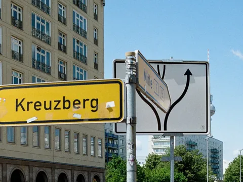 Cartel vial amarillo hacia Kreuzberg frente a edificios y cielo azul en Berlín.