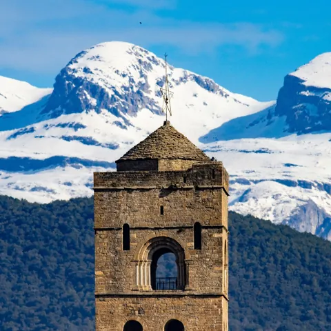 Primer plano de la torre de Aínsa con los Pirineos nevados de fondo en Huesca.