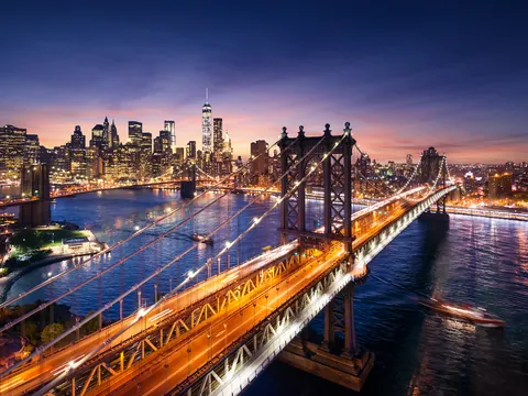 Puente de Brooklyn iluminado al anochecer con skyline de Manhattan, Nueva York, Estados Unidos