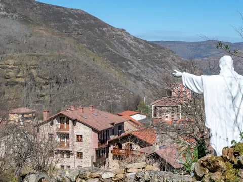 Estatua de Cristo en San Sebastián de Garabandal, con vistas al pueblo y a las montañas de los Valles Pasiegos en Cantabria.