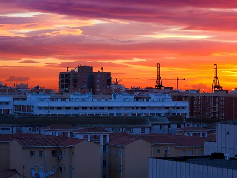 Atardecer sobre edificios y grúas del puerto de Málaga, España.