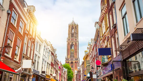 Calle típica de Utrecht, Países Bajos, con fachadas de edificios históricos a ambos lados y tiendas con toldos de colores.
