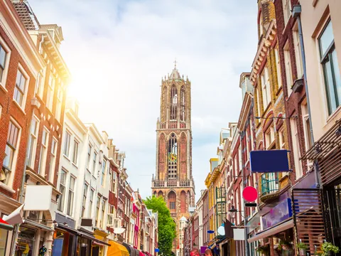 Calle típica de Utrecht, Países Bajos, con fachadas de edificios históricos a ambos lados y tiendas con toldos de colores.