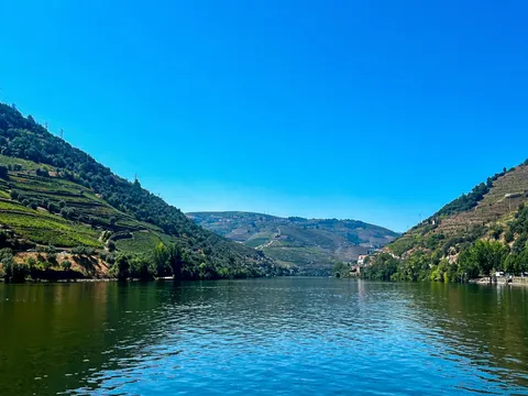 Vista del río Duero entre colinas con terrazas de viñedos bajo un cielo despejado.