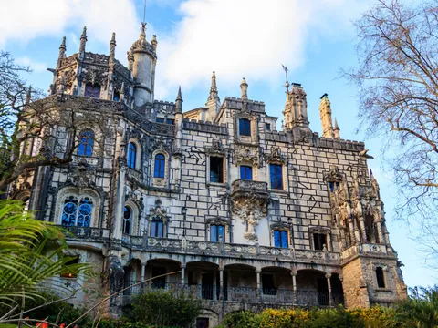 Fachada principal del palacio de Quinta da Regaleira entre árboles en Sintra