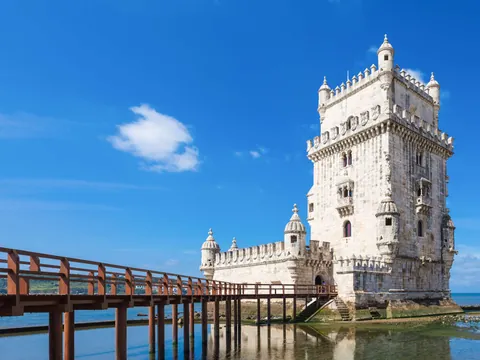 Torre de Belém reflejada en el agua bajo un cielo azul en Lisboa