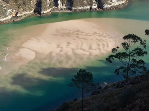 Banco de arena y aguas turquesas en la costa de Pechón, Cantabria.