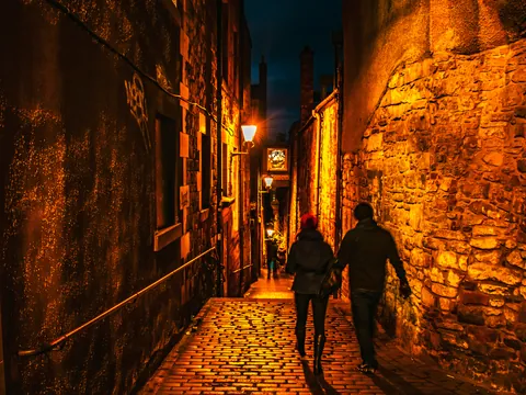 Callejón nocturno del Old Town de Edimburgo con visitantes caminando