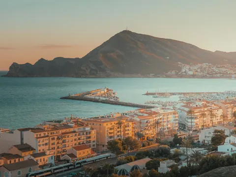 Vista panorámica de la ciudad de Altea, el puerto deportivo y la montaña del Parque Natural de Sierra Helada al atardecer.