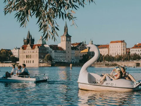Gente navegando en hidropedales de cisne en el río Moldava con el horizonte de Praga.