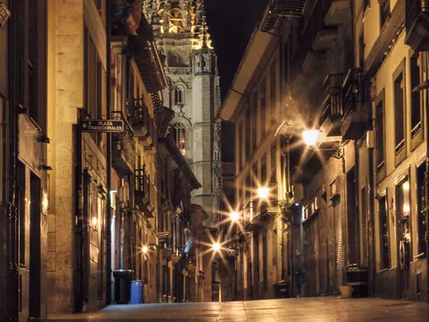 Fachada del Ayuntamiento de Oviedo iluminada de noche, con reflejos sobre el suelo mojado en la Plaza de la Constitución.