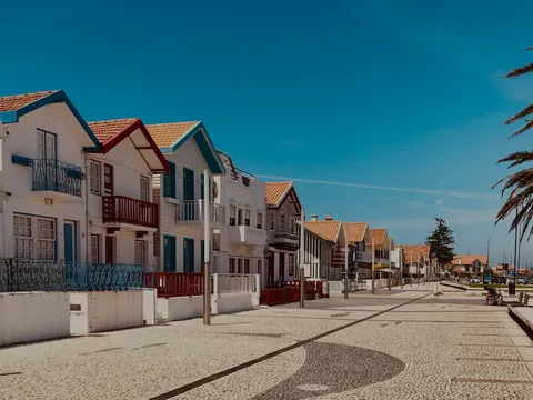 Casas de rayas típicas de Costa Nova junto al paseo marítimo en un día soleado.