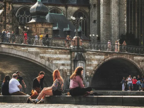 Personas paseando y descansando junto a un puente en el centro histórico de Gante