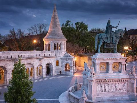 Estatua y torre cónica del Bastión de los Pescadores en Budapest al anochecer.
