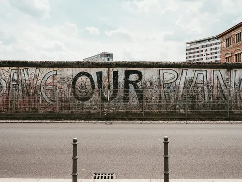 Tramo del Muro de Berlín con grafiti que dice ‘Save Our Planet’ bajo un cielo nublado