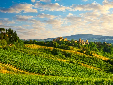 Paisaje de viñedos y pueblo medieval en colinas de la Toscana, Italia