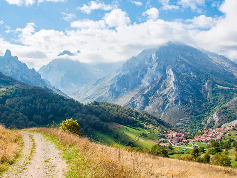 Sendero con vistas a un pueblo y los Picos de Europa