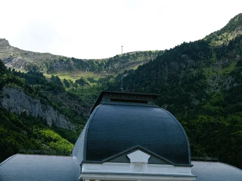 Cúpula y tejado del vestíbulo central de la Estación Internacional de Canfranc con las montañas al fondo.