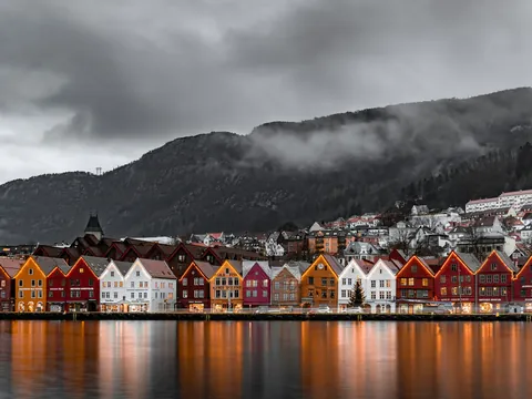 Famoso muelle de Bryggen en Bergen, Noruega, con casas de madera coloridas reflejadas en el agua al anochecer.