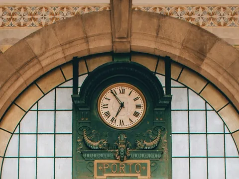 Reloj histórico de la estación de tren São Bento en Oporto, rodeado de azulejos tradicionales portugueses.