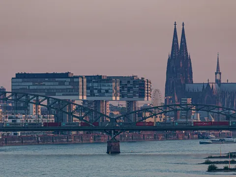 Puente ferroviario y Catedral de Colonia sobre el río Rin al anochecer.