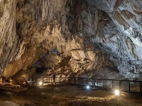 Interior de la cueva Cullalvera iluminado, con estalactitas y pasarela para visitantes en un amplio espacio
