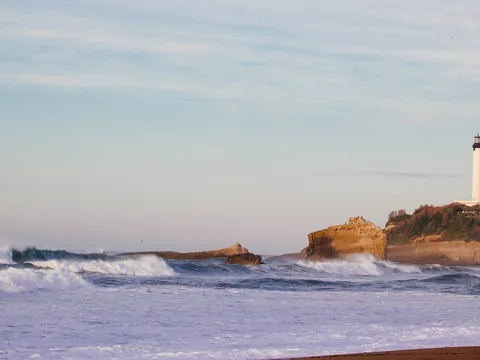 Faro de Biarritz sobre el acantilado con olas rompiendo en la costa.