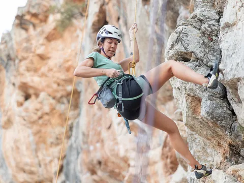 Escaladora realizando un descenso en rappel por una pared de roca en El Chorro
