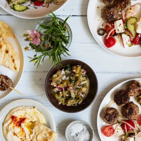 Varios platos de comida griega con brochetas, pan pita y hummus en Atenas