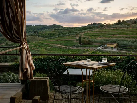 Mesa servida en una terraza con vistas a los viñedos de la Toscana