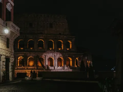 Coliseo de Roma iluminado de noche visto desde una calle cercana y tranquila