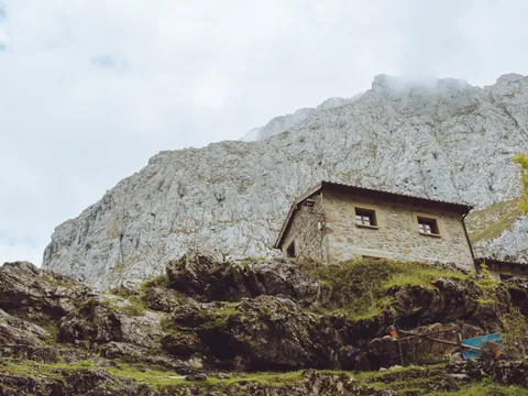 Casa de piedra en el pueblo de Bulnes, construida sobre la ladera rocosa de los Picos de Europa y rodeada de naturaleza.