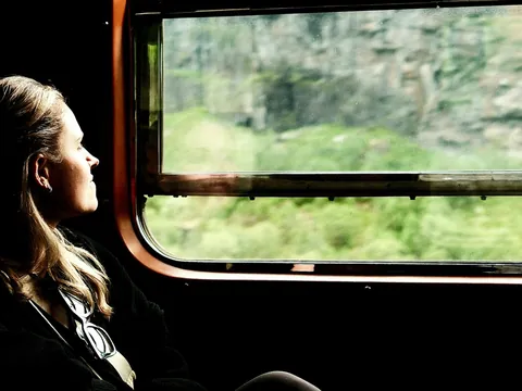 Mujer disfrutando de las vistas por la ventana del tren entre Oslo y Bergen, la famosa línea ferroviaria de Noruega.