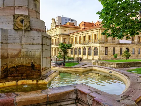 Fuente histórica en la Plaza San Isidoro, León, con el Real Colegiata de San Isidoro, arquitectura románica y jardines.