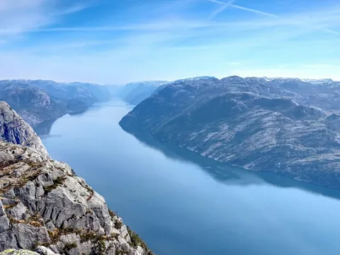 Vista panorámica del fiordo Lysefjord en Noruega, con acantilados rocosos y aguas tranquilas bajo cielo despejado.