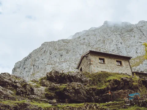 Casa de piedra en el pueblo de Bulnes, construida sobre la ladera rocosa de los Picos de Europa y rodeada de naturaleza.
