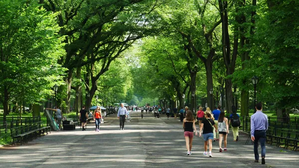 Paseo frondoso en Central Park con visitantes caminando bajo la vegetación, Estados Unidos
