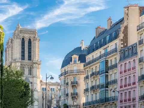 Edificios históricos en París con fachada de piedra y tejados inclinados bajo cielo parcialmente nublado.