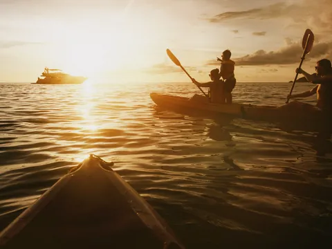 Grupo en kayak y barco en el mar durante un atardecer en Es Grau, Menorca