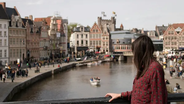 Mujer observando las casas y el canal desde un puente en Gante, Bélgica