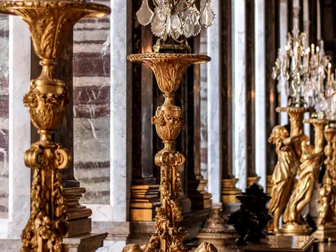 Estatuas doradas y lámparas en un largo pasillo del exterior del Palacio de Versalles.