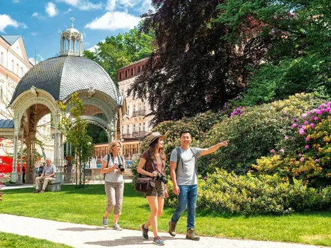 Excursionistas caminando por el parque de la Columnata de la Fuente en Karlovy Vary