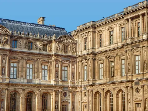 Palacio del Louvre, famoso museo de arte en París, con su icónica pirámide de vidrio en el patio central.