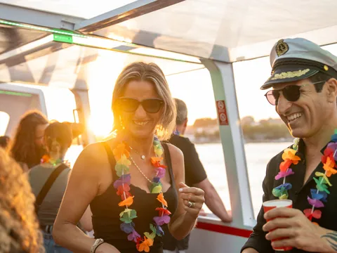 Personas disfrutando de una fiesta en barco al atardecer en Oporto.