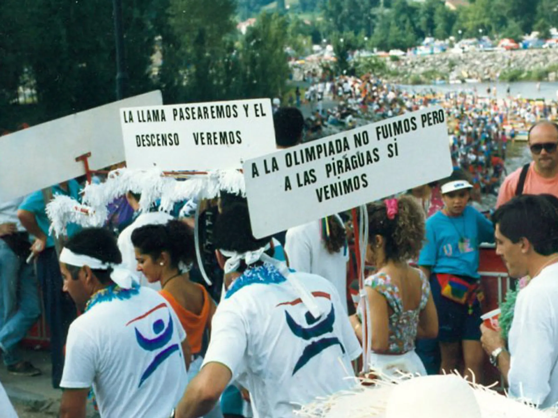 Piragüeros de fiesta en la salida del Descenso del Sella con un cartel cómico en Arriondas, Asturias