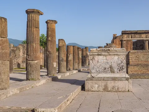 Ruinas clásicas con columnas de piedra y altar de mármol bajo cielo despejado.