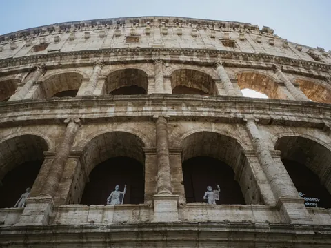 Fachada del Coliseo de Roma vista desde abajo con arcos y estatuas en las galerías
