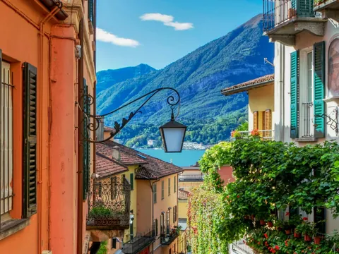 Calle colorida con vista al Lago di Como y montañas al fondo