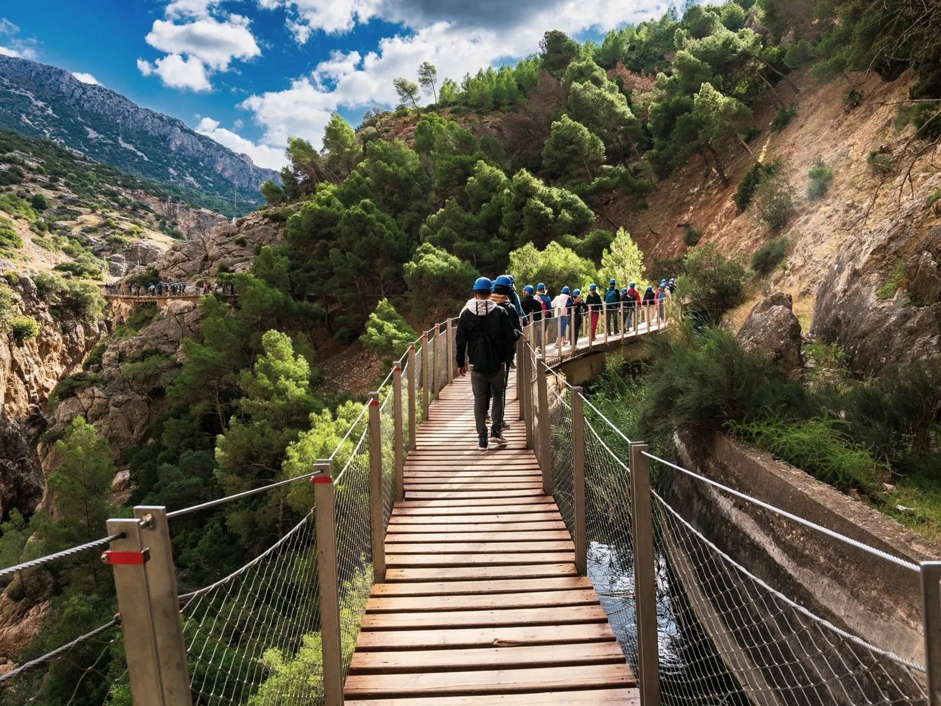Grupo de visitantes con cascos azules caminando por el Caminito del Rey